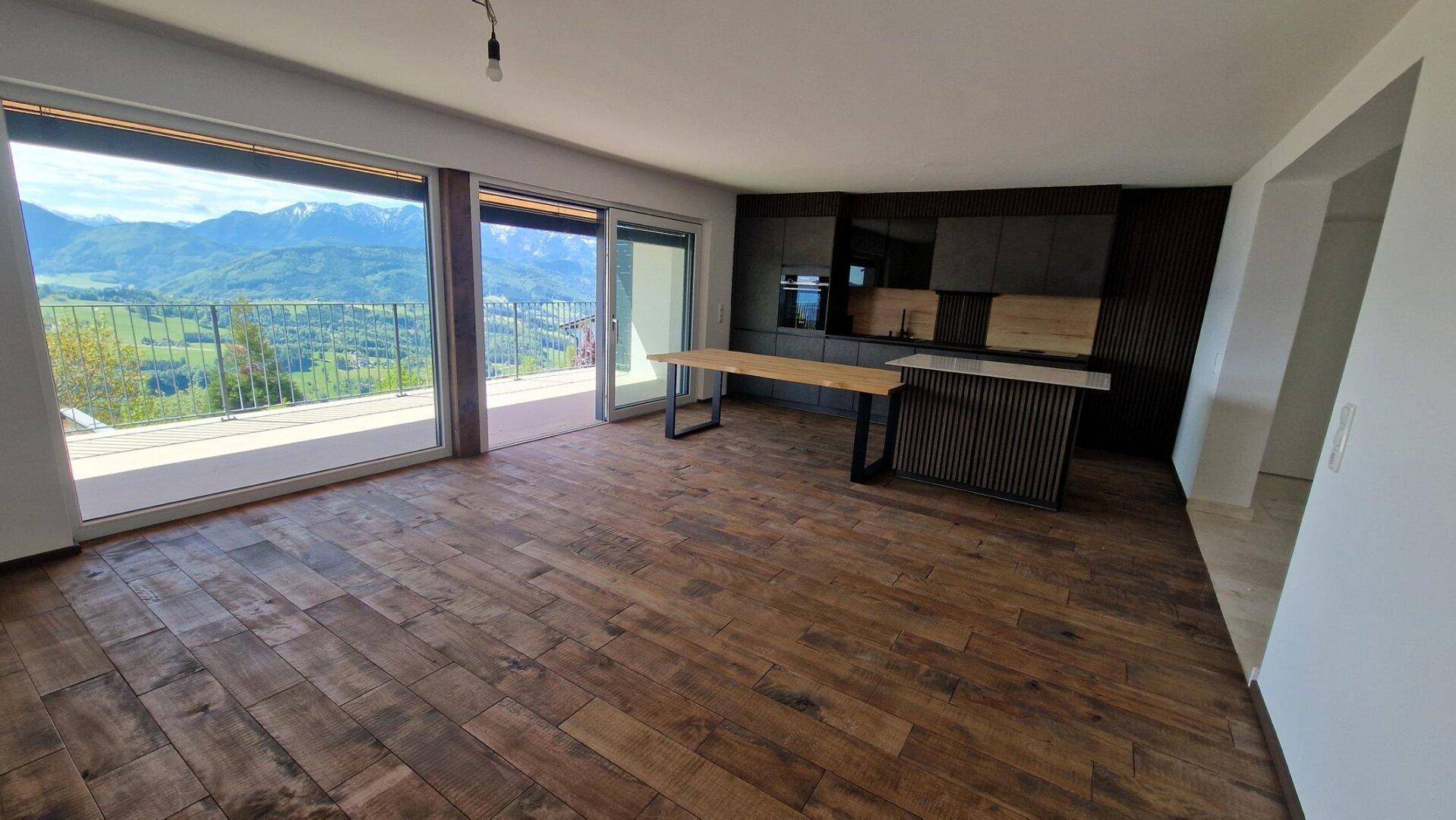 Geräumiger offener Wohn- und Essbereich mit Holzboden und großen Fenstern mit Bergblick.
