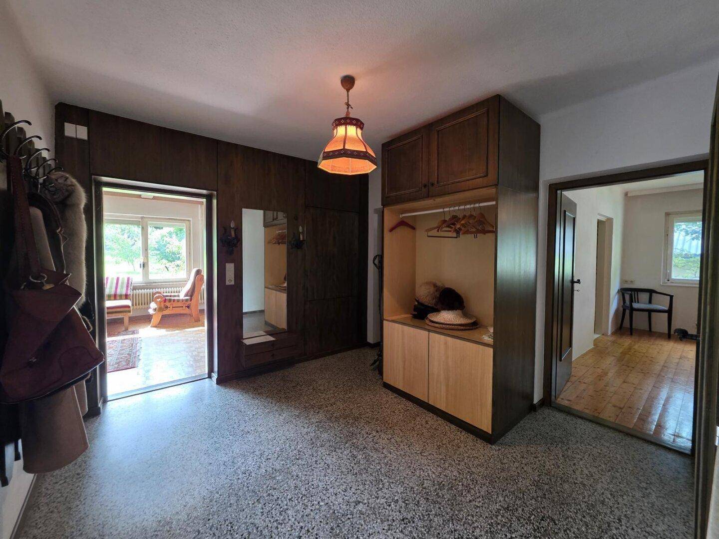 Eingangsbereich mit Terrazzoboden, Holzvertäfelung und praktischen Einbauschränken.