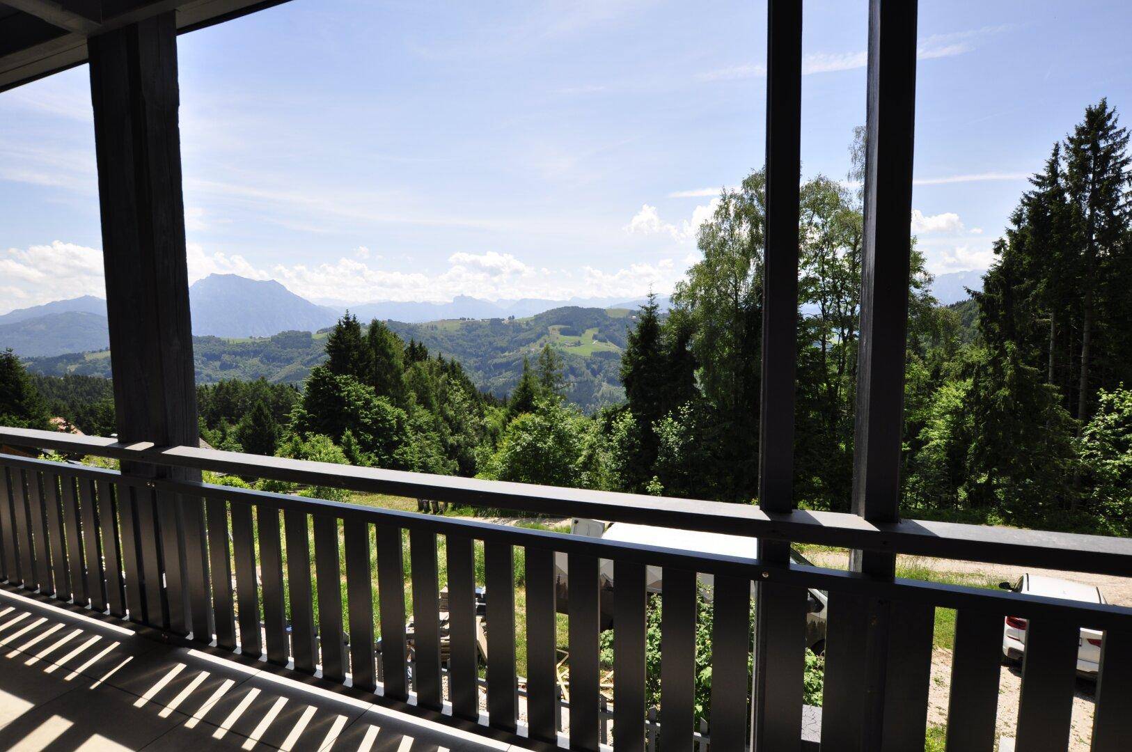 Geräumiger Balkon mit Holzboden und atemberaubendem Blick auf die umliegende Berglandschaft und Wälder.