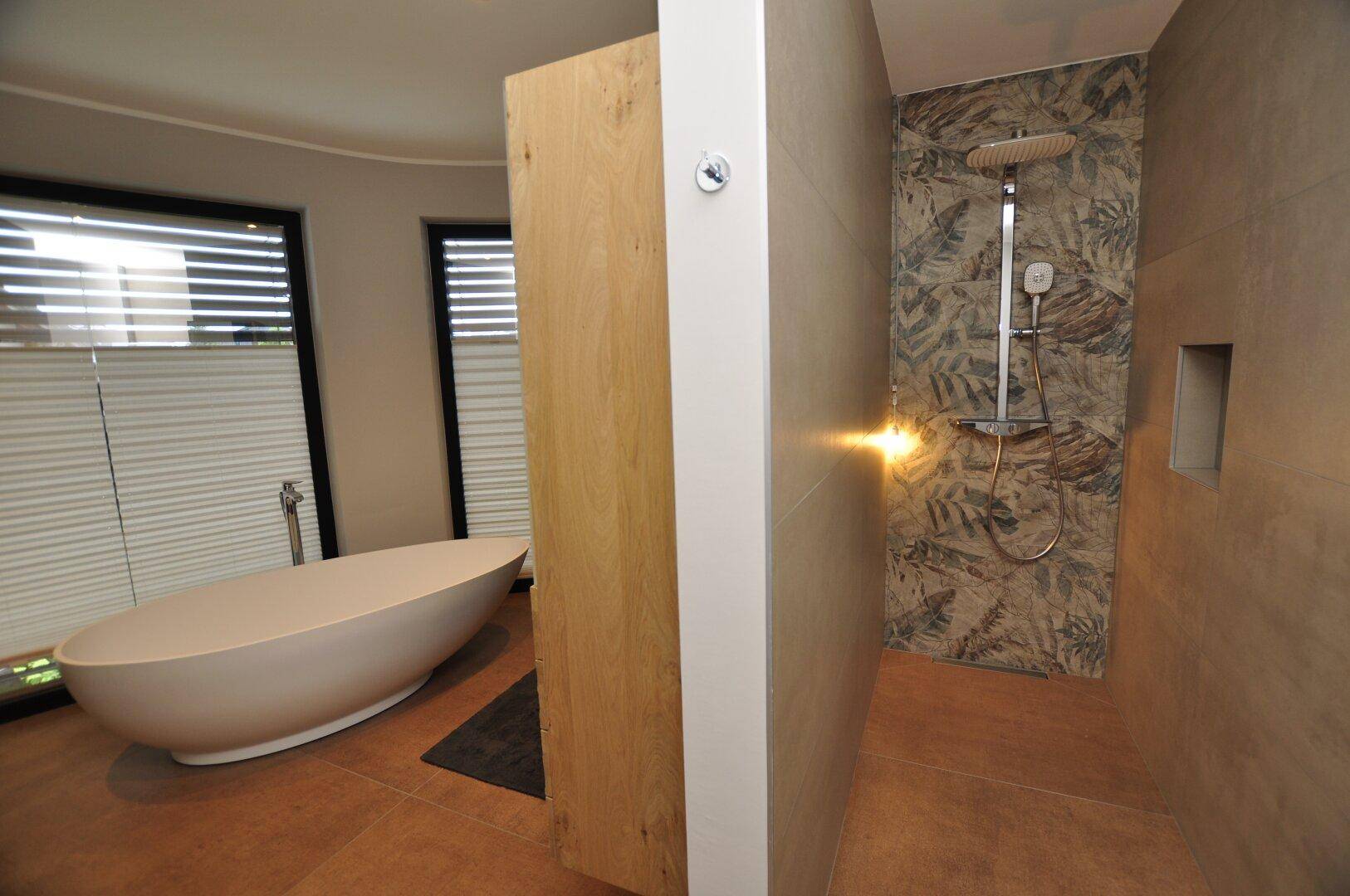 Geräumiges Badezimmer mit moderner Duschkabine, Regendusche und freistehender Badewanne.