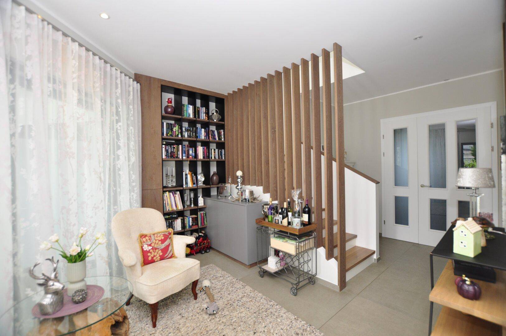 Heller Eingangsbereich mit offener Treppe, Bücherregal und stilvoller Dekoration.