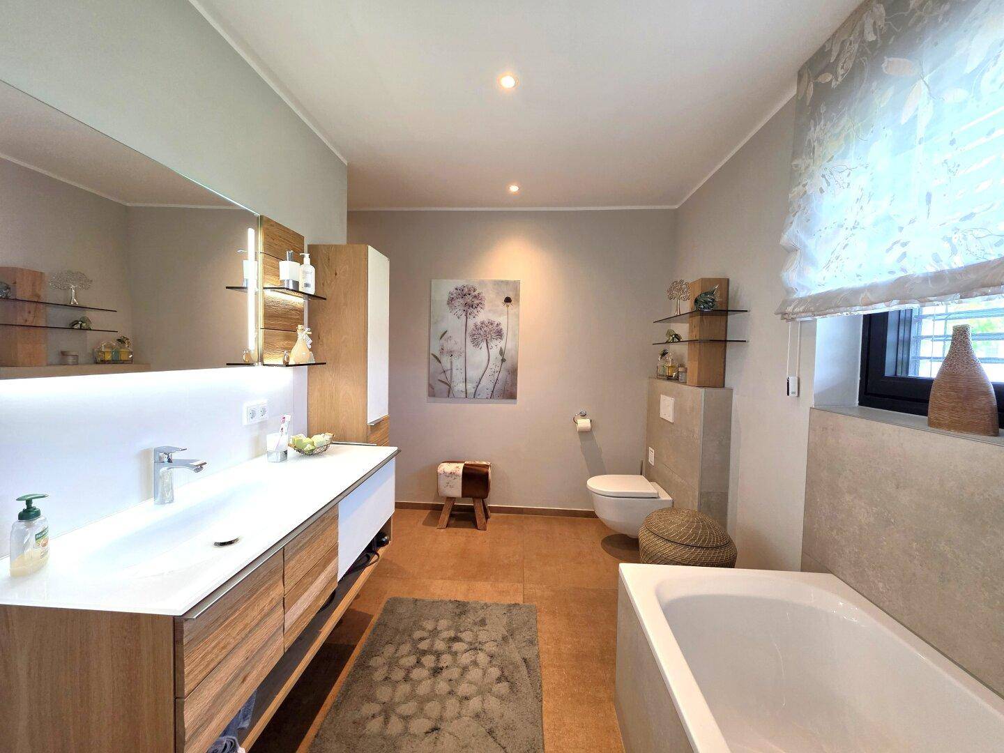 Helles Badezimmer mit breitem Waschtisch, großem Spiegel mit Beleuchtung und integrierter Badewanne.