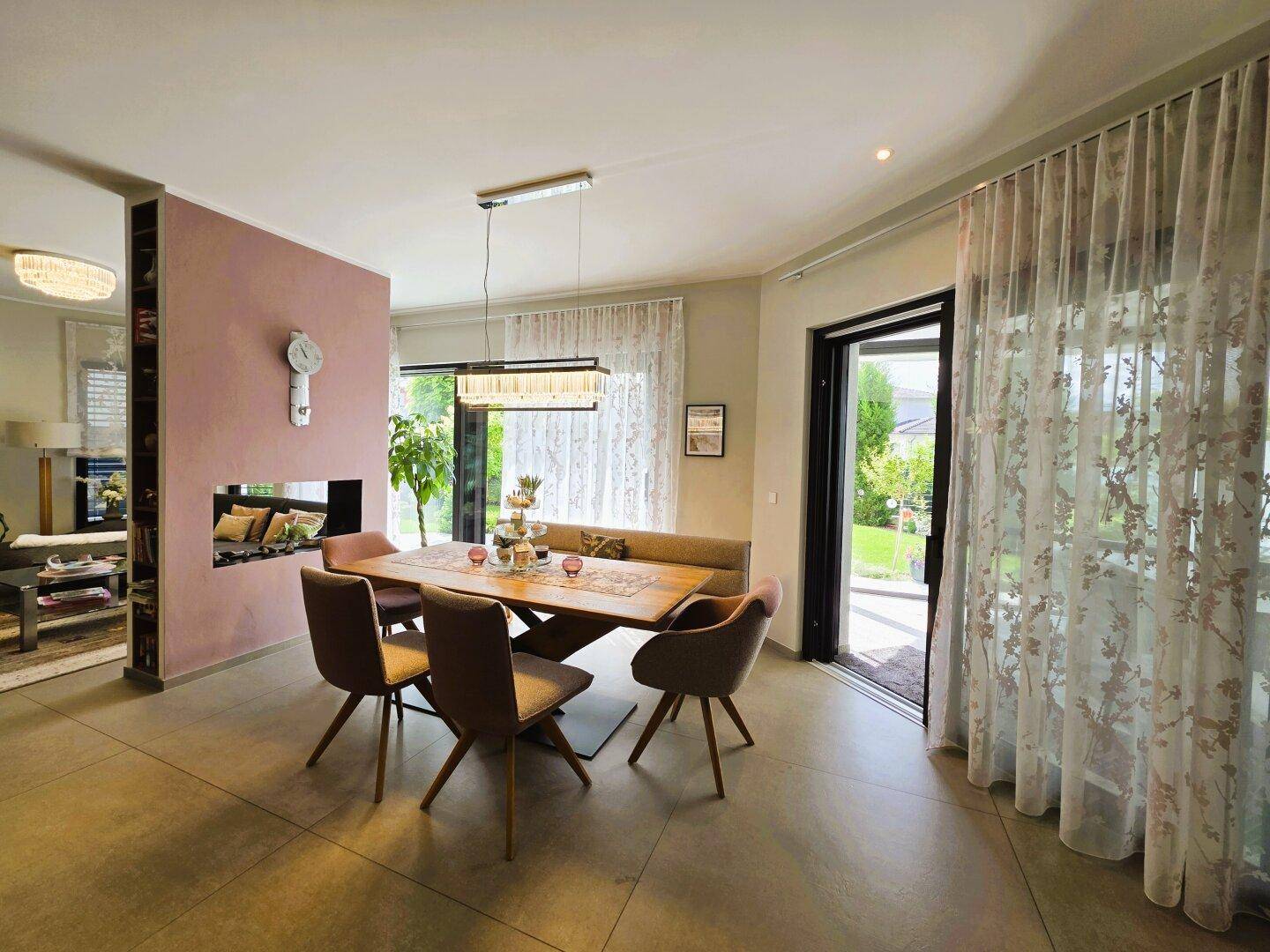 Eleganter Essbereich mit großem Holztisch, modernen Stühlen und einem integrierten Kamin in der Wand.