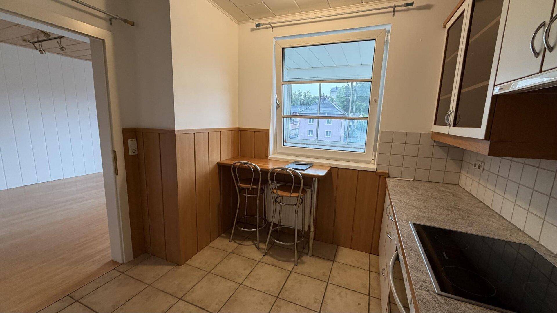Gemütlicher Essbereich in der Küche mit Holztäfelung unter dem Fenster.