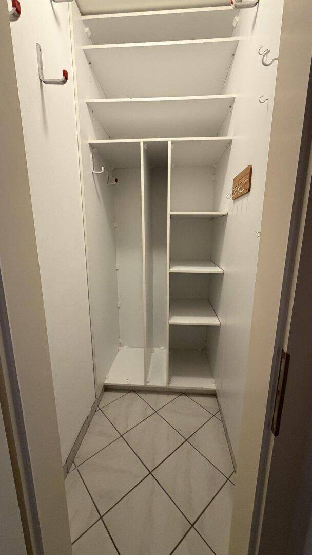 Praktischer Einbauschrank mit Regalen und Kleiderstange, ideal als Stauraum.