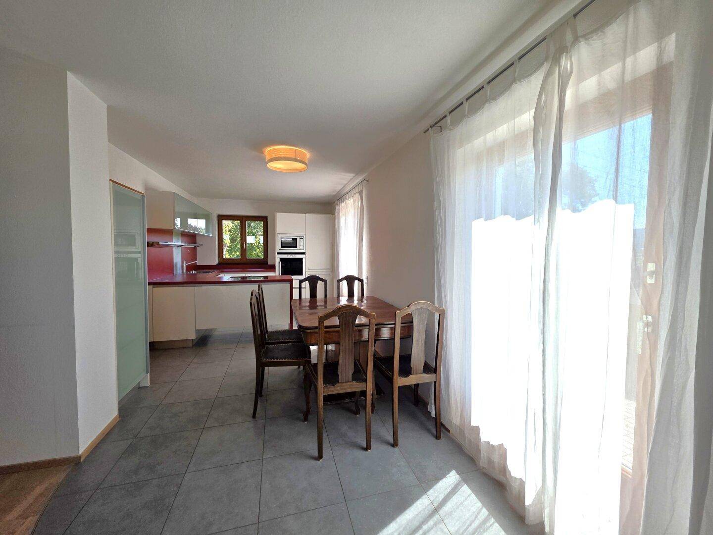 Heller Essbereich in der Küche mit großem Fenster und Zugang zu einem Außenbereich.