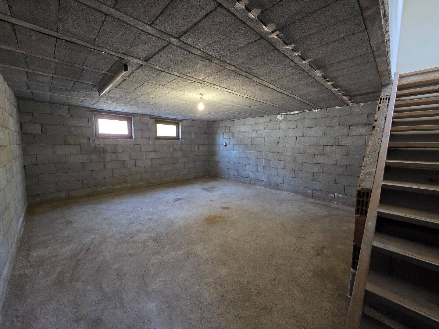 Kellerraum mit Betonblockwänden und kleinen Fenstern, ideal als Lagerfläche.