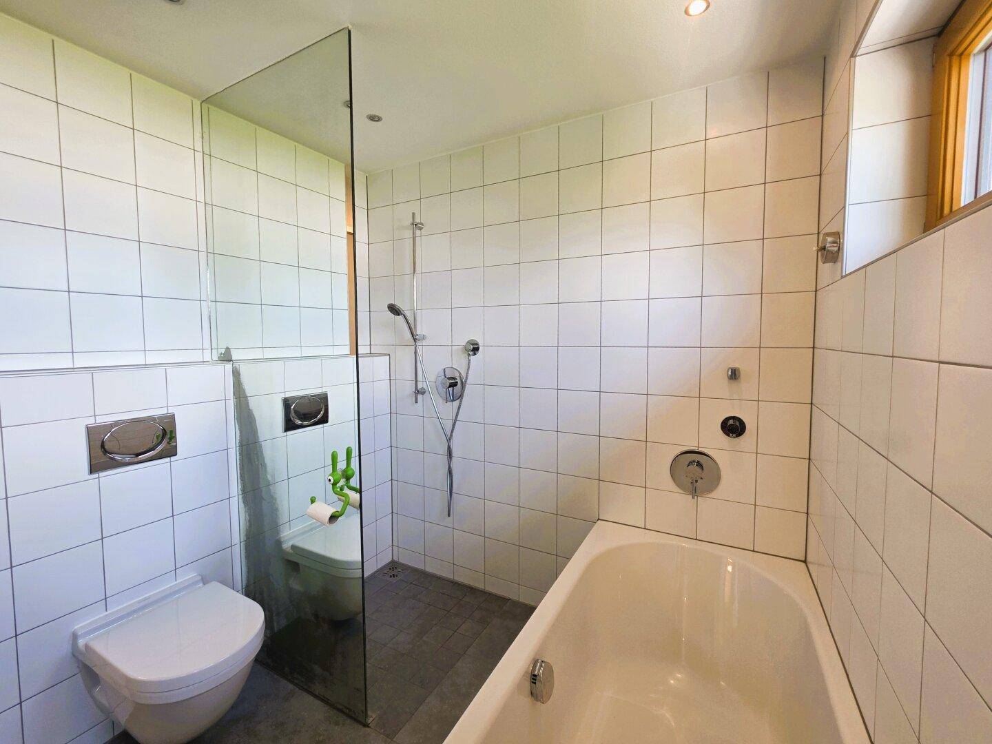 Helles Badezimmer mit Badewanne, Dusche und wandhängendem WC.