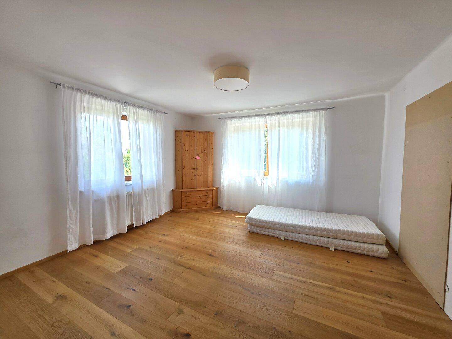 Geräumiges Schlafzimmer mit Holzboden, großen Fenstern und viel natürlichem Licht.