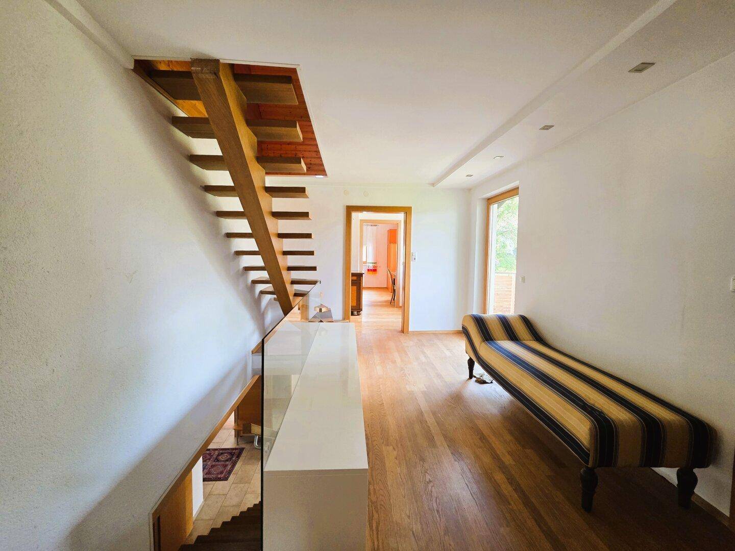 Geräumiger Flur mit offener Holztreppe und Sitzbank.