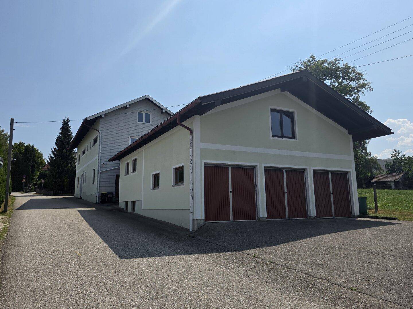 Gesamtansicht des Wohnhauses und des separaten Garagengebäudes an einem sonnigen Tag.