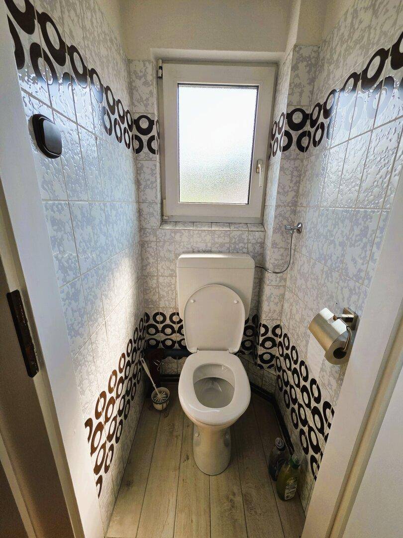 Kleines WC mit Fenster und auffälligen Fliesen im Retro-Stil, praktisch und hell.