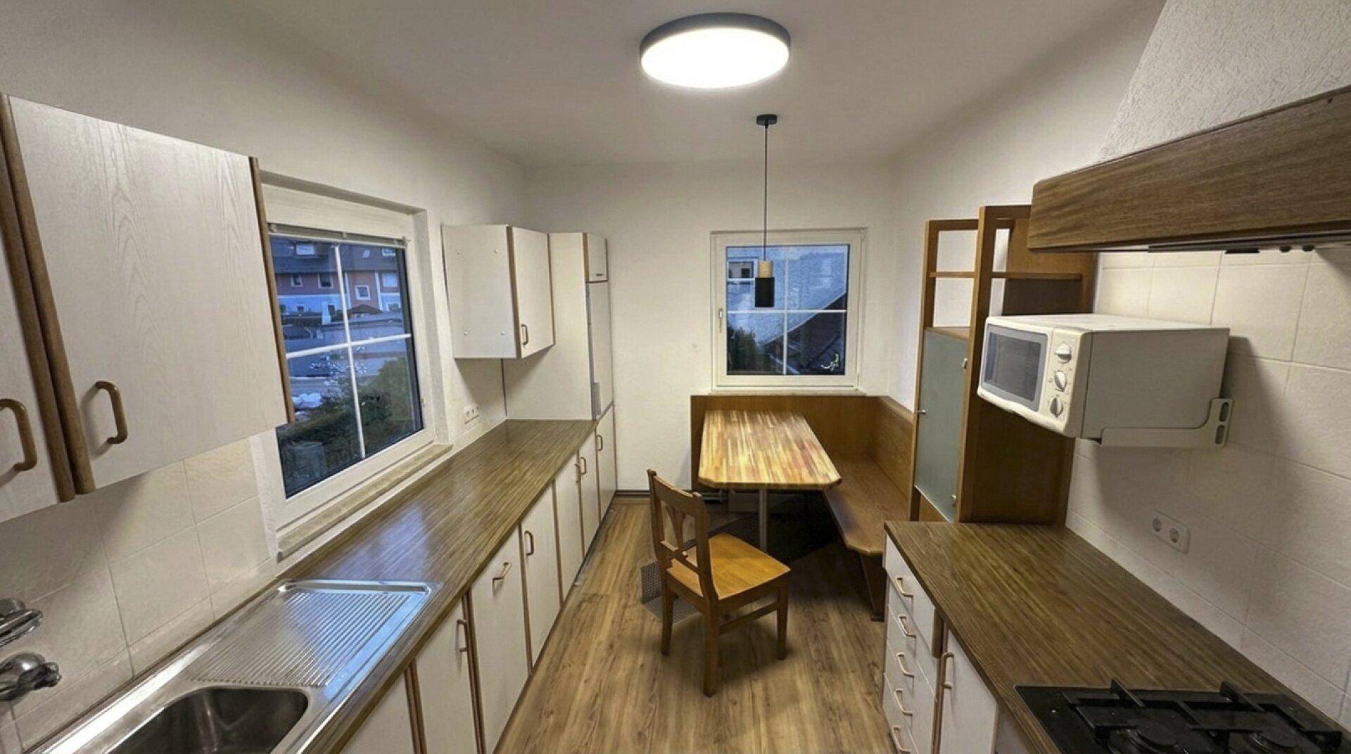 Funktionale Küche mit Essbereich, Mikrowelle und Fensterblick auf die Umgebung.