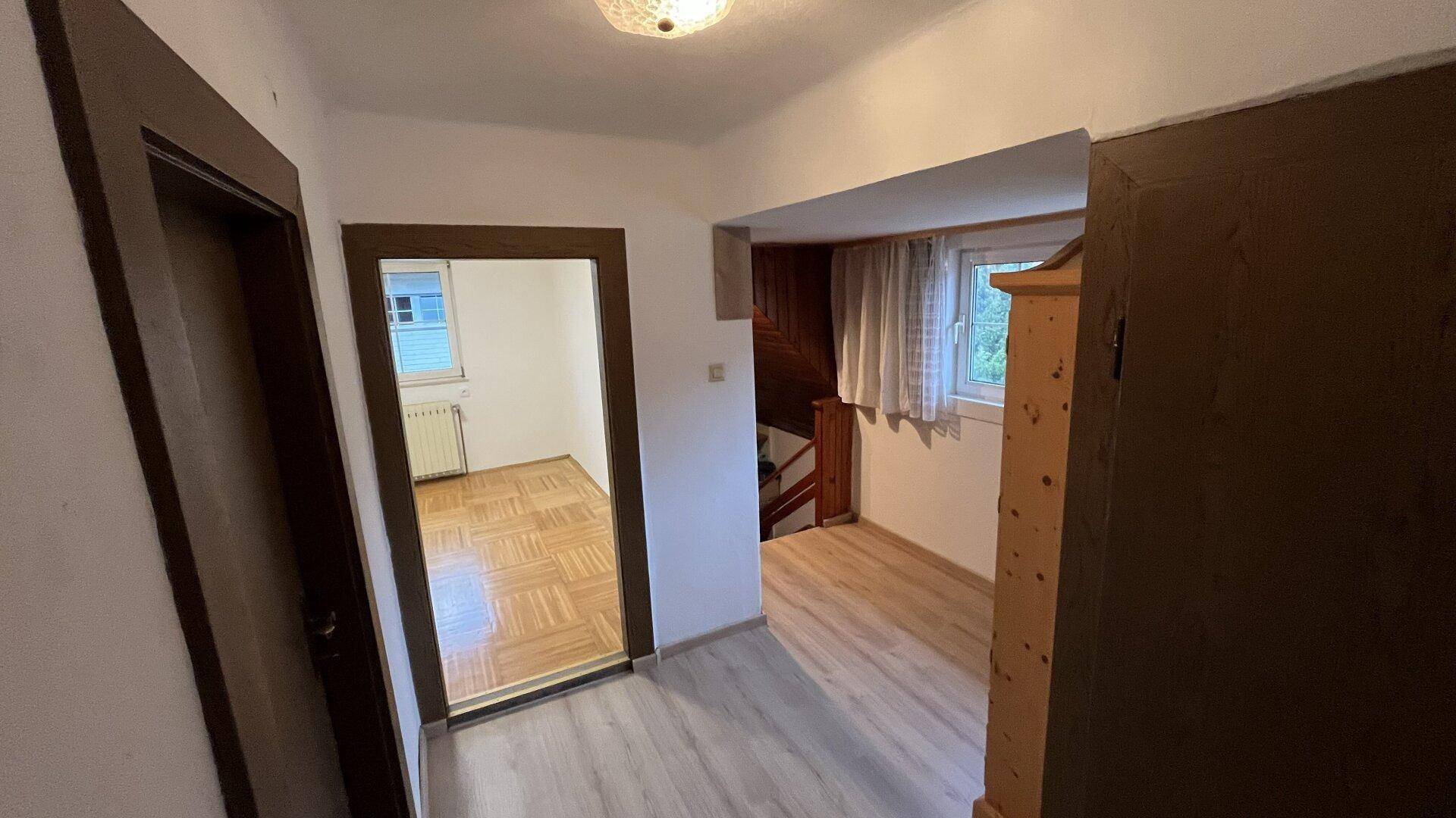 Heller Flur mit Laminatboden und Blick in angrenzende Zimmer, die viel Licht bieten.