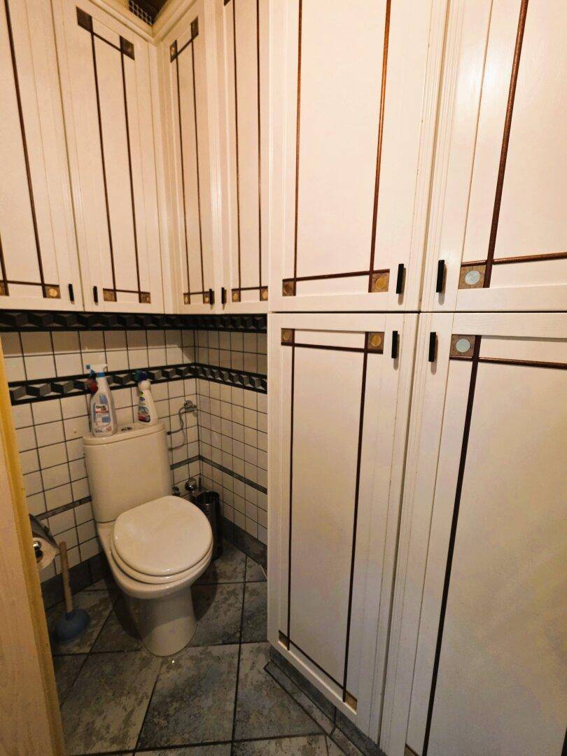 Kleines Gäste-WC mit WC und Fliesenboden, umgeben von praktischen Einbauschränken.
