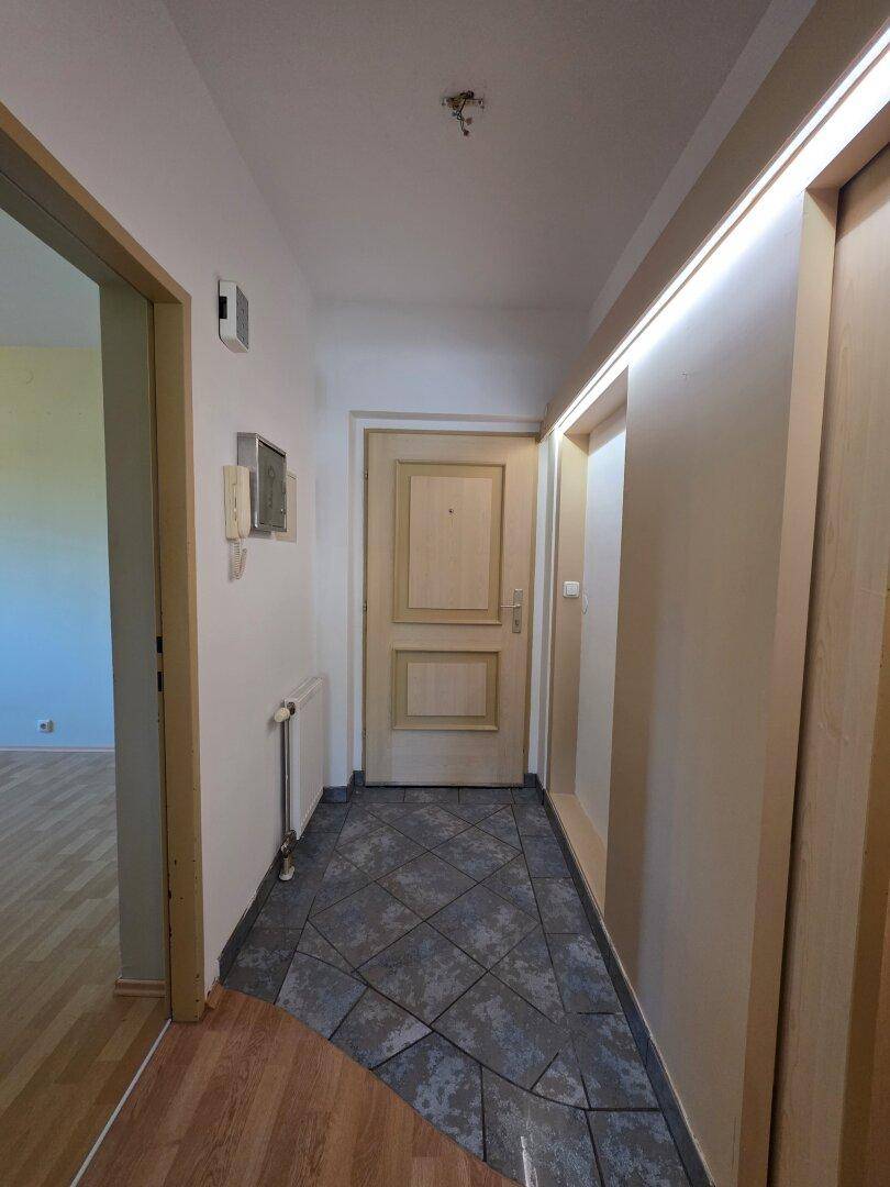 Heller Eingangsbereich mit Fliesenboden und Holztür, führt zu den weiteren Räumen der Wohnung.