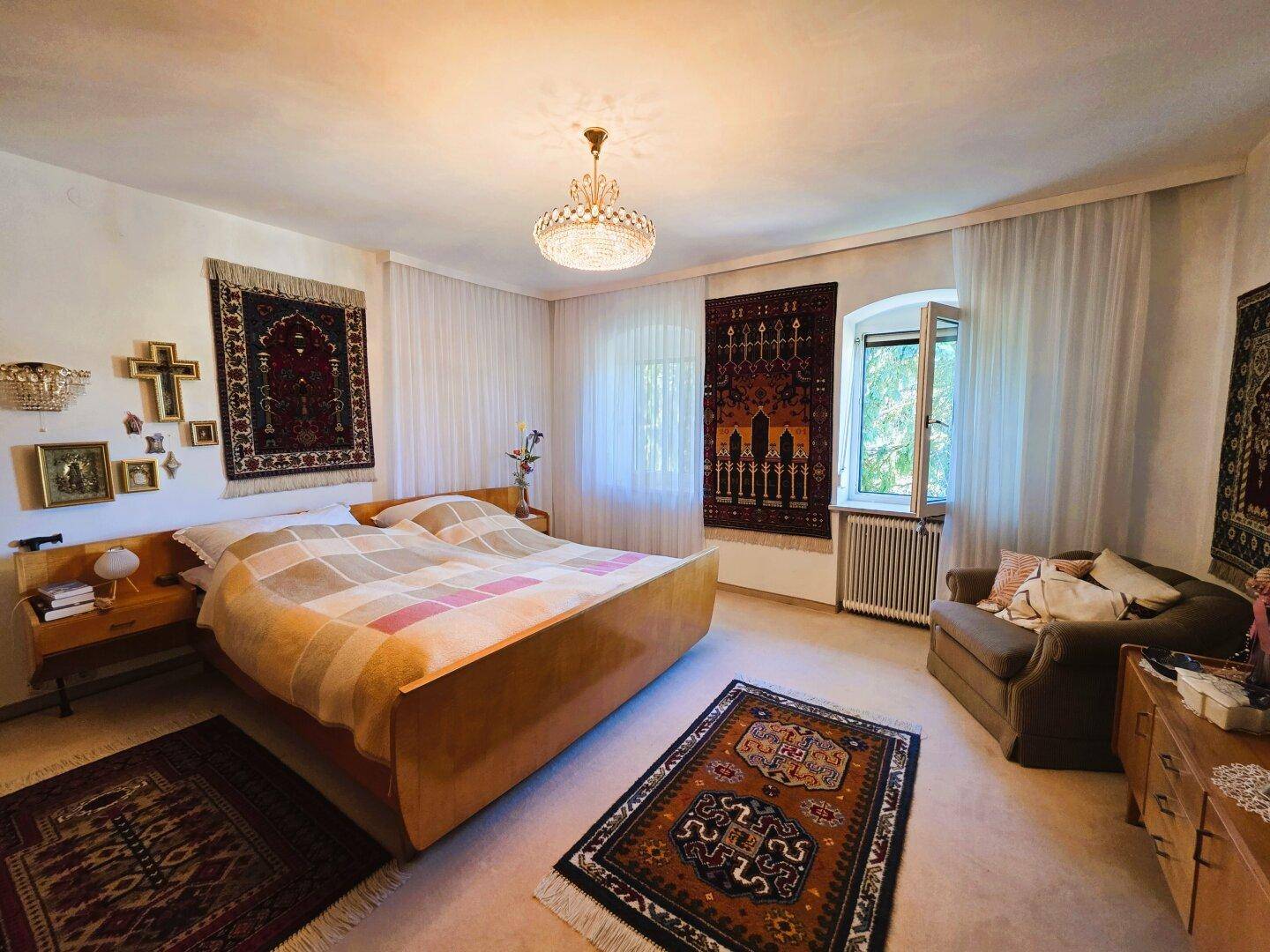 Geräumiges Schlafzimmer mit großem Bett, bequemer Sitzecke und traditionellen Teppichen als Dekoration.