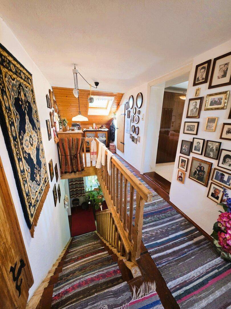 Rustikaler Treppenaufgang und Flur mit Holzvertäfelung, Dachfenster und einer Galerie von Familienfotos.