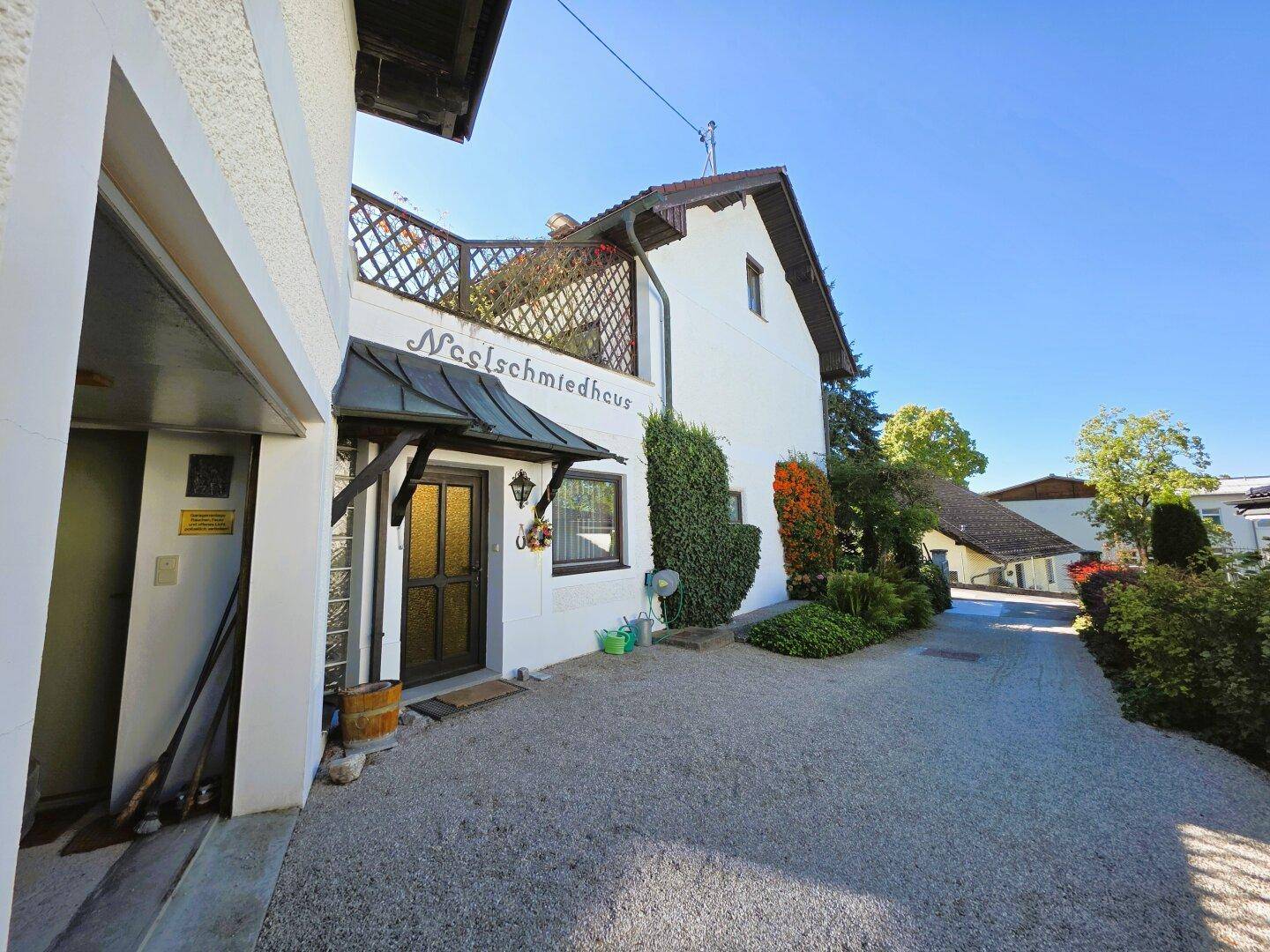 Haupteingang des Hauses mit überdachtem Bereich, Kiesauffahrt und angrenzender Garage.