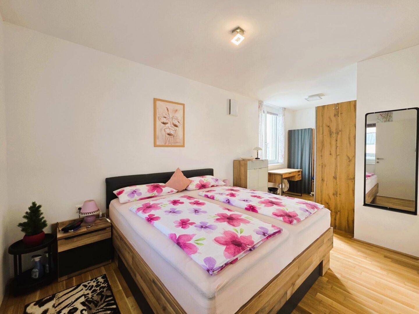 Gemütliches Schlafzimmer mit Doppelbett, Holzmöbeln und einem großen Spiegel.