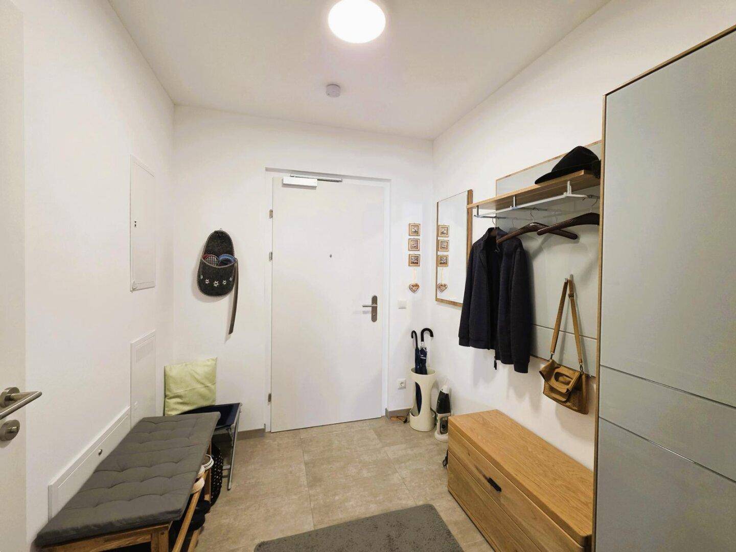 Heller Eingangsbereich mit Garderobe, Sitzbank und Stauraum für Schuhe.