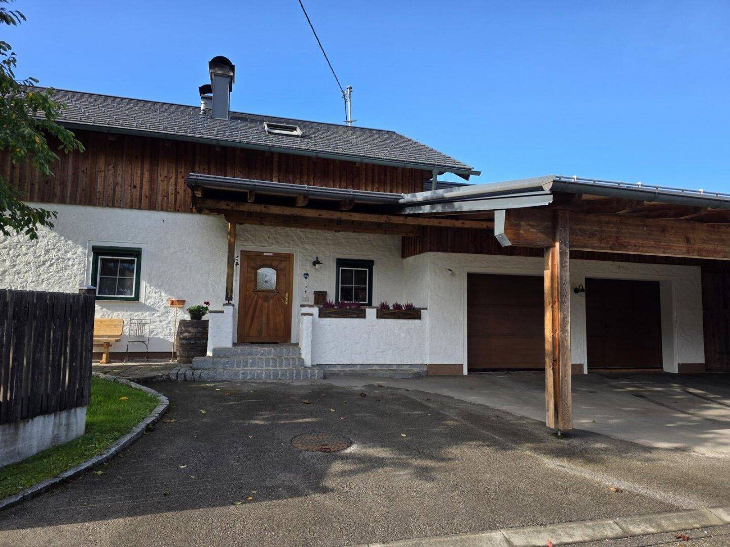 Vorderansicht des Hauses mit Carport, Einfahrt und traditionellem Eingangsbereich.
