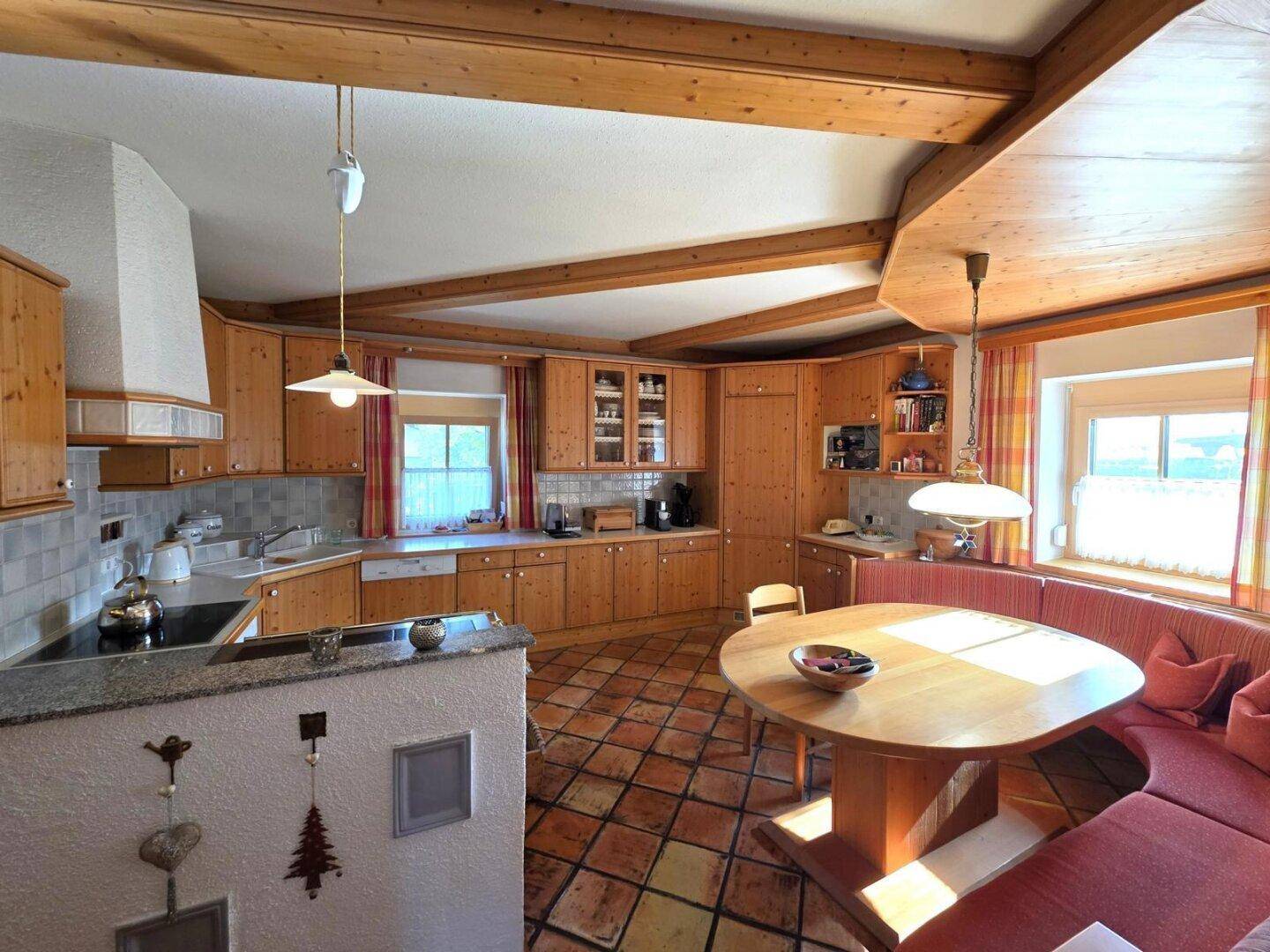 Gemütliche Holzküche im Landhausstil mit Essbereich und sichtbaren Deckenbalken.