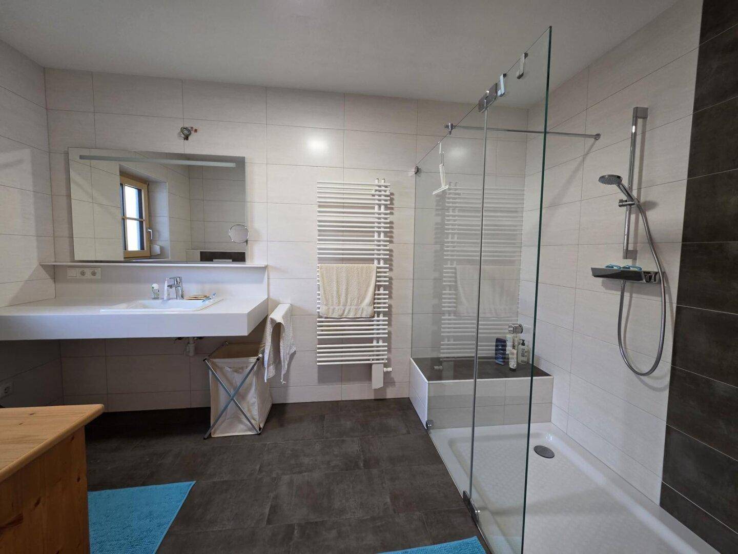 Modernisiertes Badezimmer mit ebenerdiger Dusche, großem Waschbecken und beheiztem Handtuchhalter.