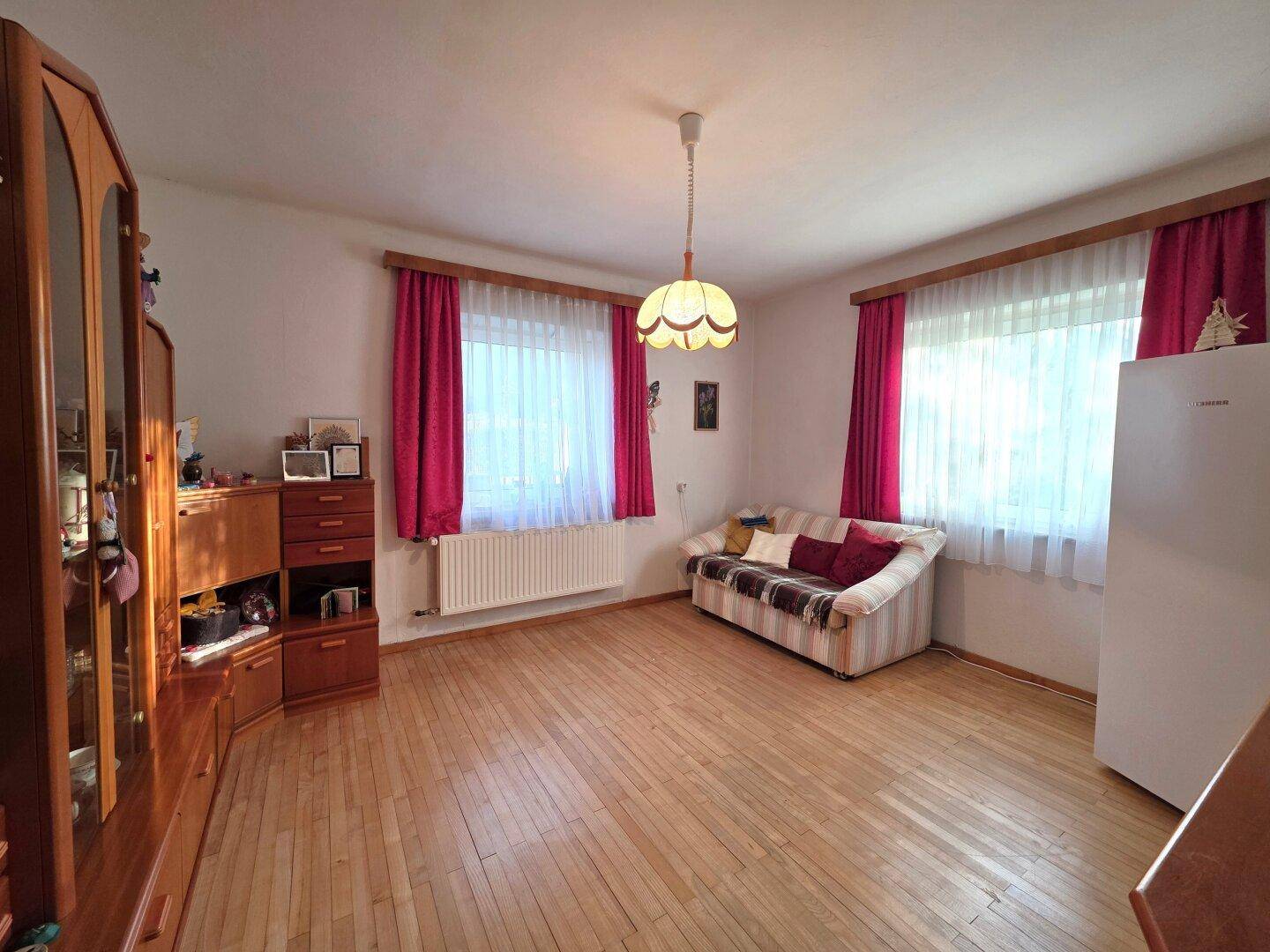 Geräumiges Wohnzimmer mit Holzparkett, Sofa und großem Holzschrank.