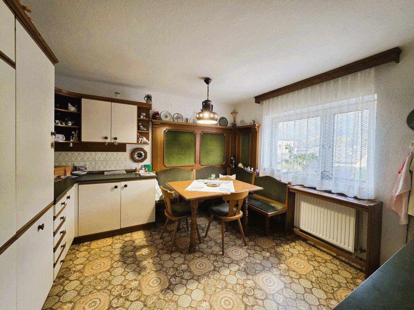 Traditionelle Küche mit Essbereich, Holzmöbeln und gemustertem Fliesenboden.