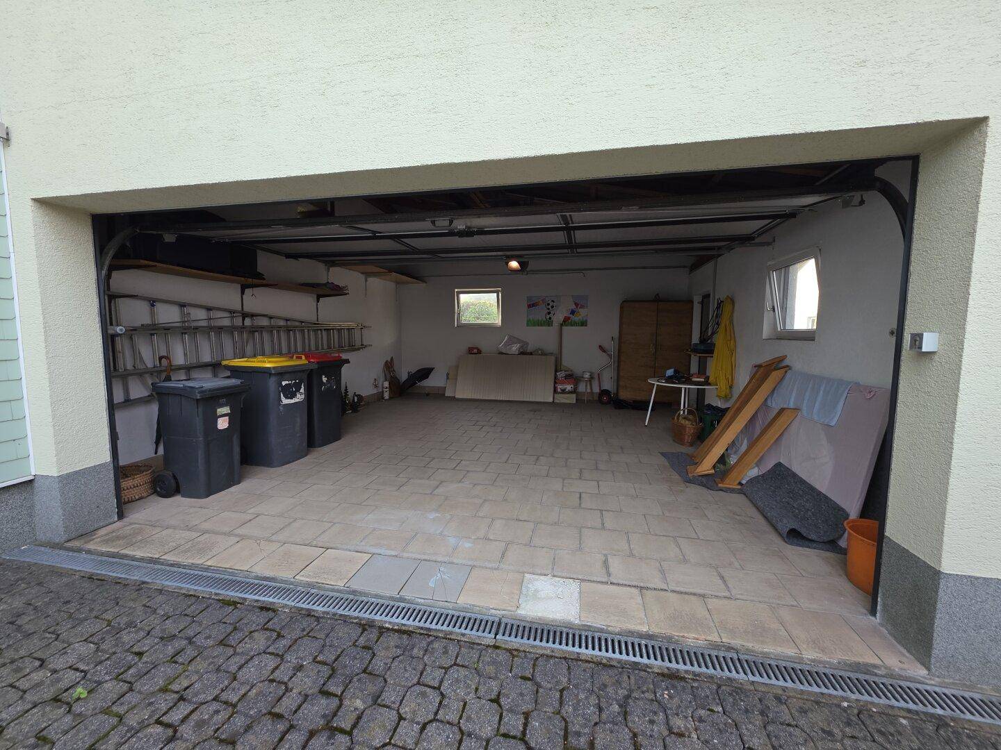 Geräumige Doppelgarage mit gepflastertem Boden und Stauraum.