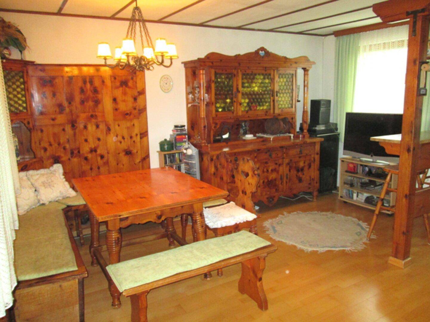 Rustikaler Essbereich mit Holztisch, Bänken und traditionellen Holzmöbeln.