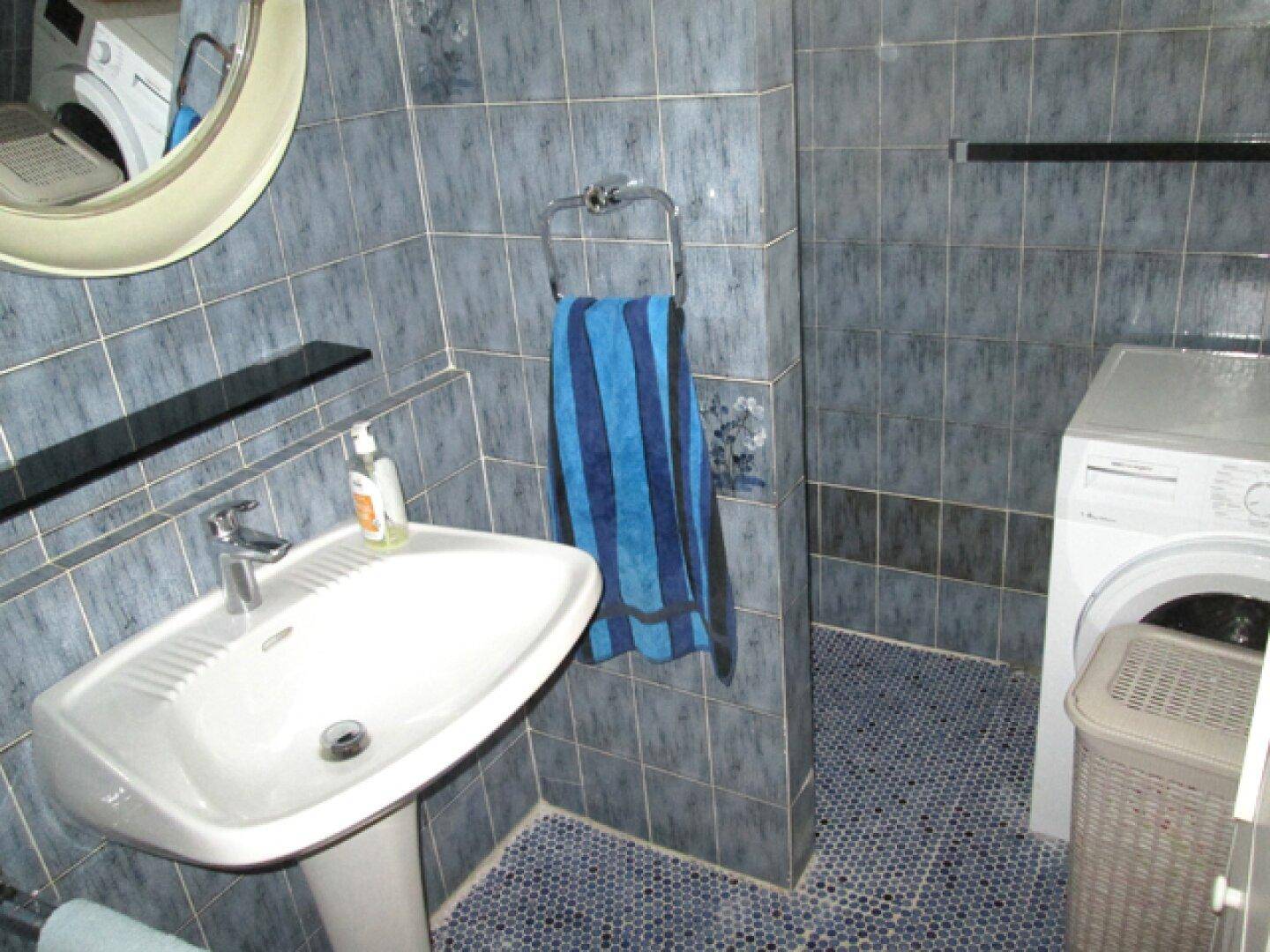 Badezimmer mit blauen Fliesen, Waschbecken und Waschmaschine.