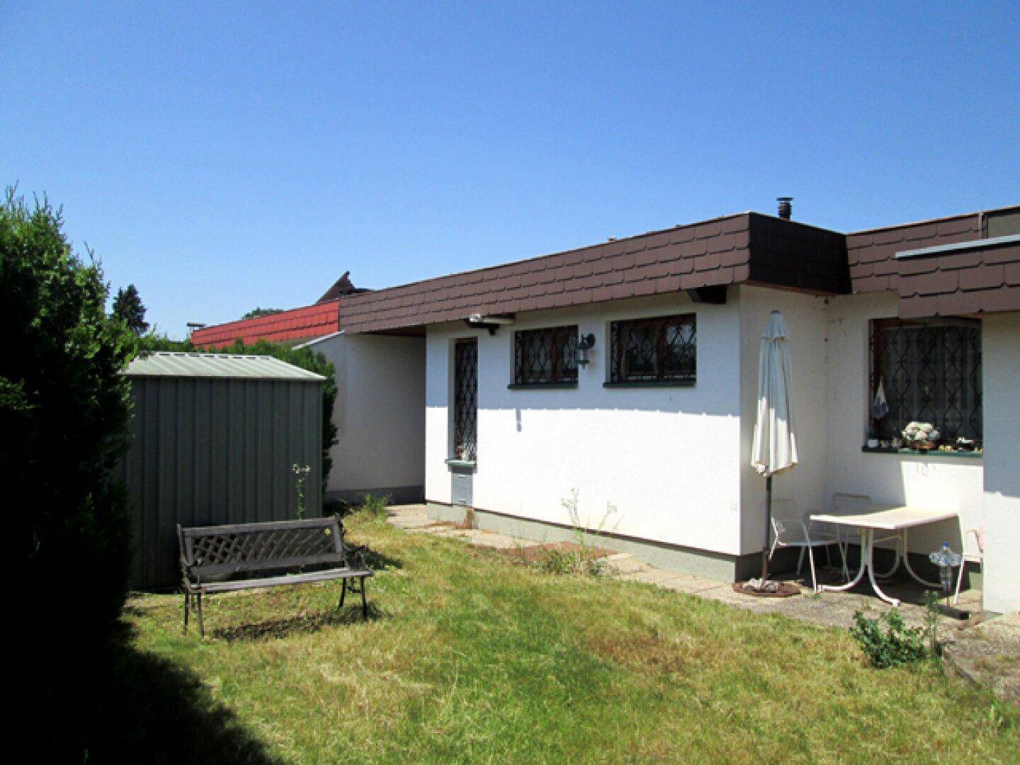 Seitenansicht des Hauses mit Garten, Schuppen und kleiner Terrasse.