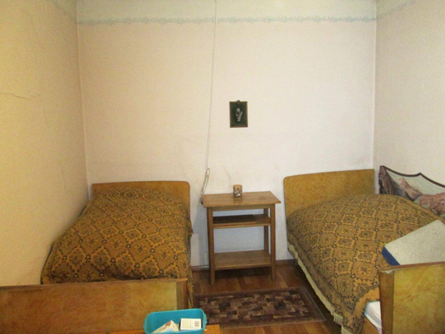 Schlafzimmer mit zwei Einzelbetten, einem Nachttisch und Holzboden.