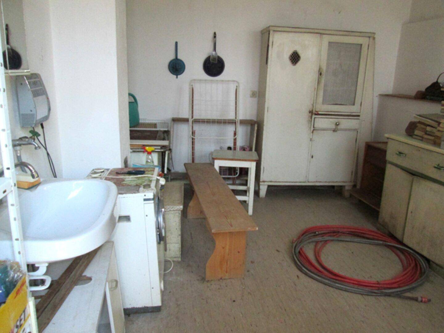 Hauswirtschaftsraum mit Waschbecken, Waschmaschine und einem Holzofen.