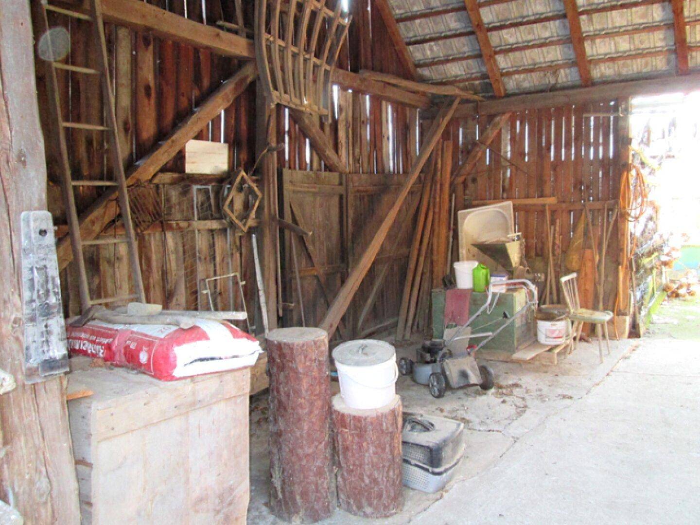 Innenansicht einer Scheune mit Holzkonstruktion, Werkzeugen und gelagertem Holz.