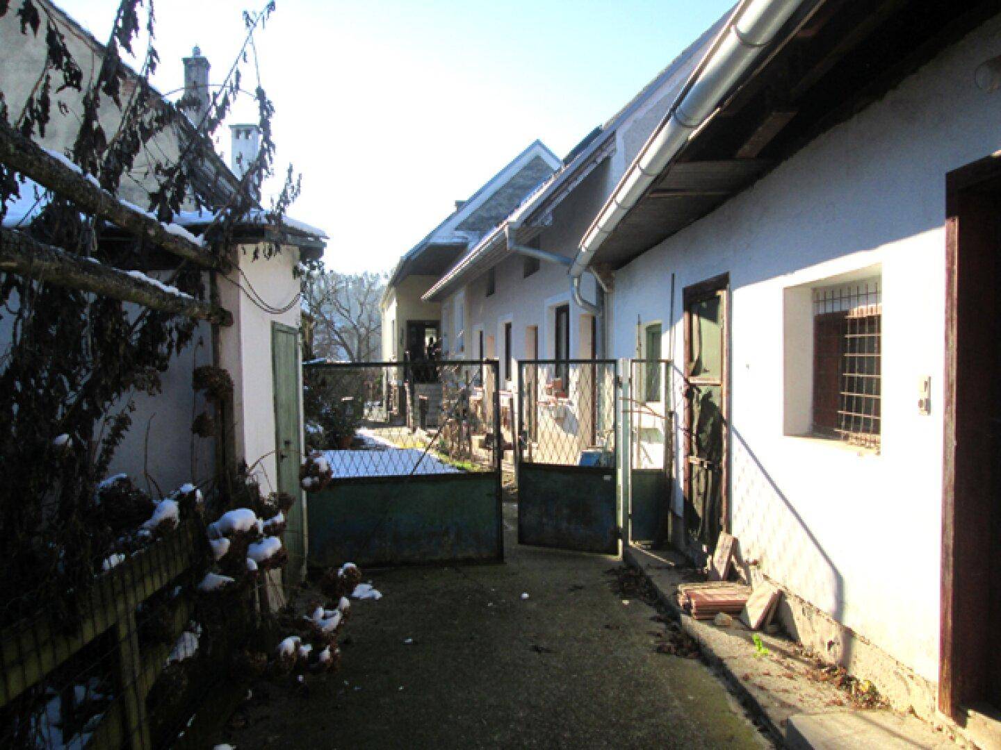 Innenhof zwischen den Gebäuden mit einem Metalltor und Spuren von Schnee auf dem Boden.