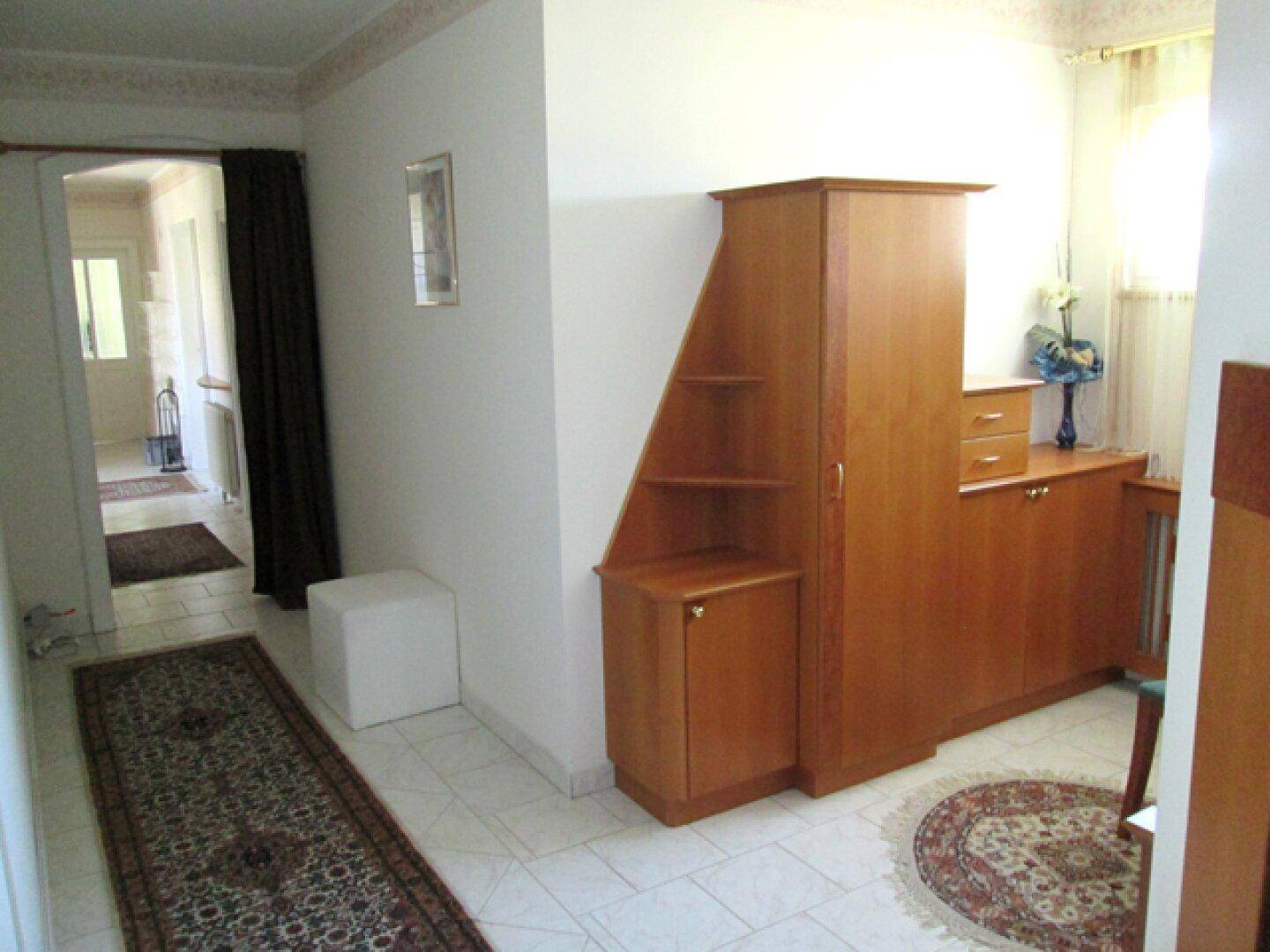Geräumiger Flur mit Fliesenboden und praktischen Einbaumöbeln aus Holz für Stauraum.