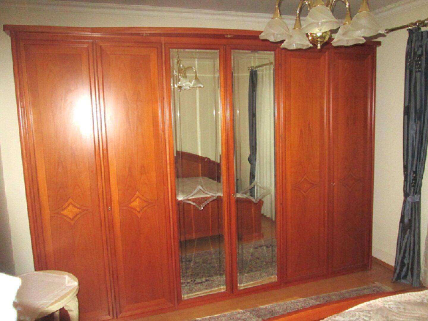 Geräumiges Schlafzimmer mit einem breiten Holzschrank, der Spiegeltüren und Stauraum bietet.