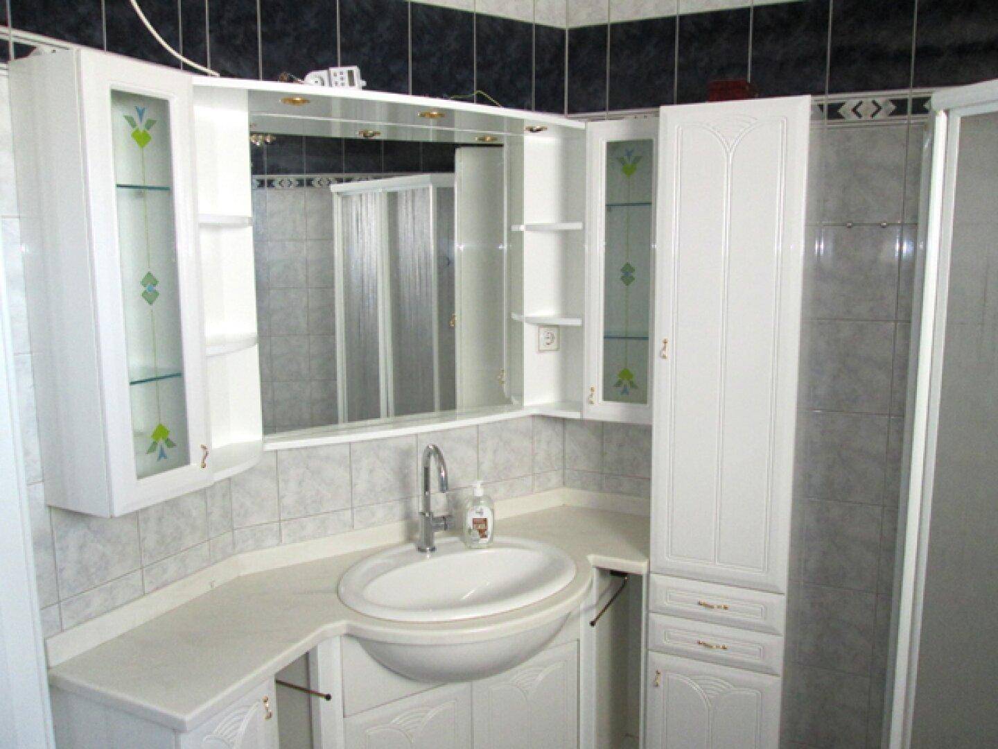 Detailansicht des Waschbeckens und Spiegelschranks im Badezimmer mit blauen und weißen Fliesen.