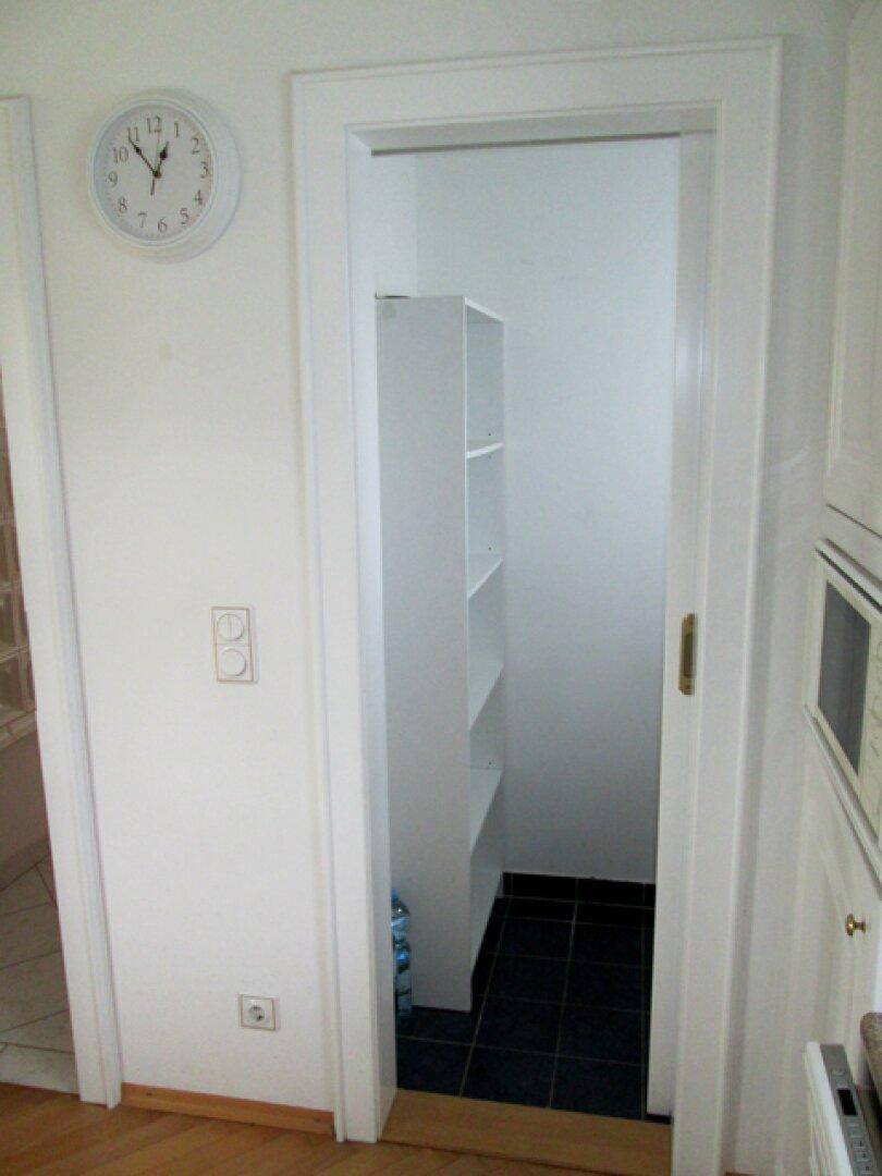 Kleine Speisekammer mit Regalen und dunklen Fliesen, ideal für Vorräte.