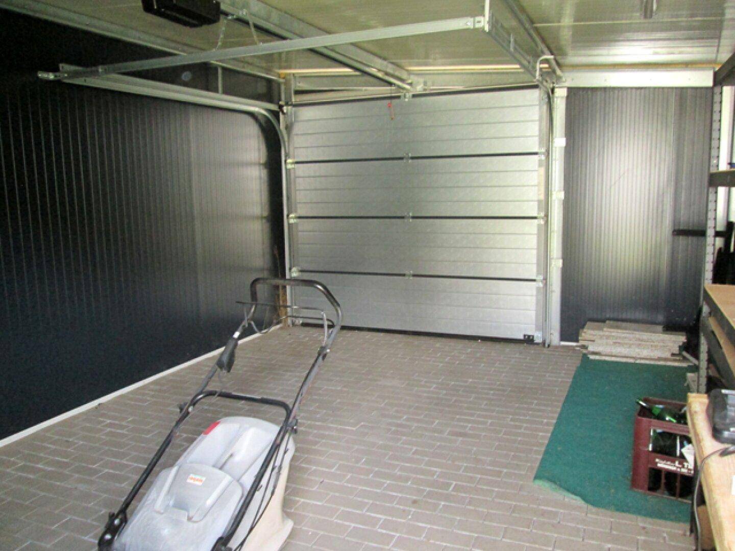 Geräumige Garage mit Sektionaltor und Platz für ein Fahrzeug sowie Werkbank.
