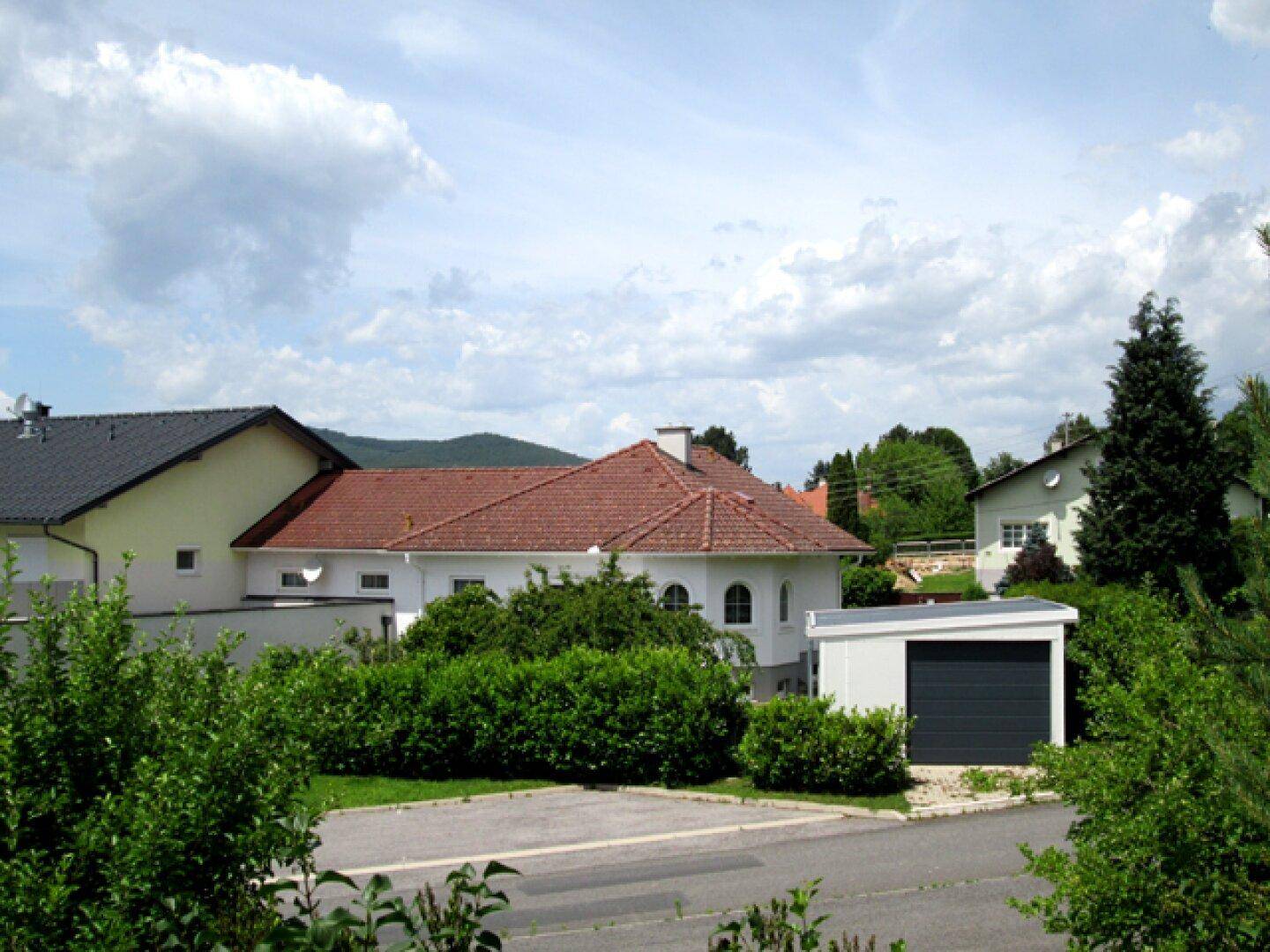 Einfamilienhaus mit rotem Ziegeldach und Garage in einer ruhigen Wohngegend.