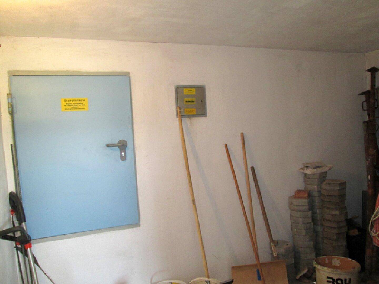 Hauswirtschaftsraum mit blauer Tür, einem Stromkasten und verschiedenen Reinigungsgeräten.