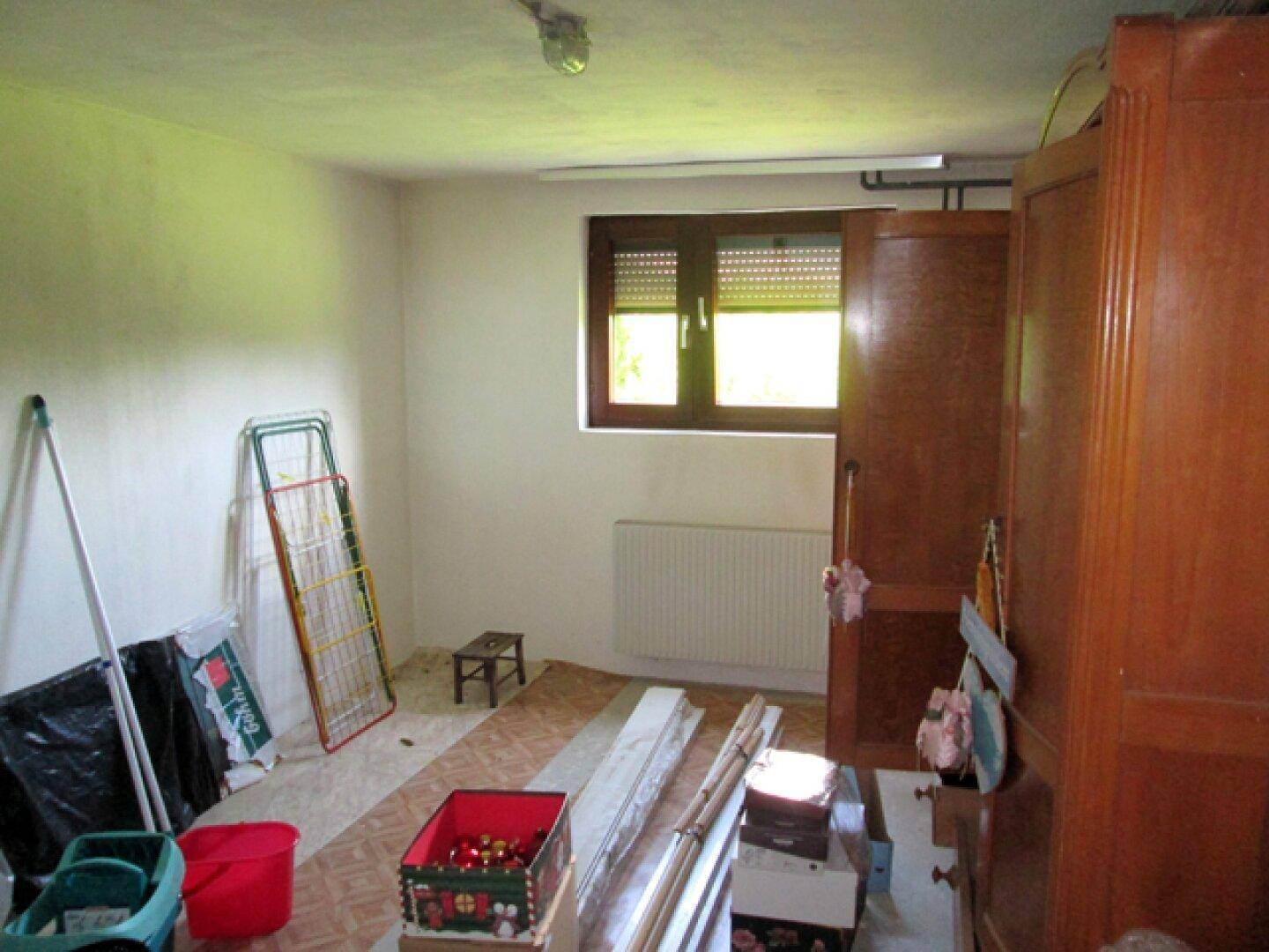 Abstellraum mit Fenster, Heizkörper und verschiedenen Gegenständen, ideal für Lagerzwecke.