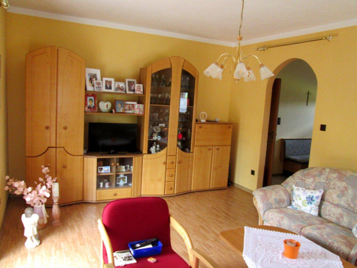 Wohnzimmer mit gelben Wänden, Holzmöbeln und einem Sofa in traditionellem Stil.
