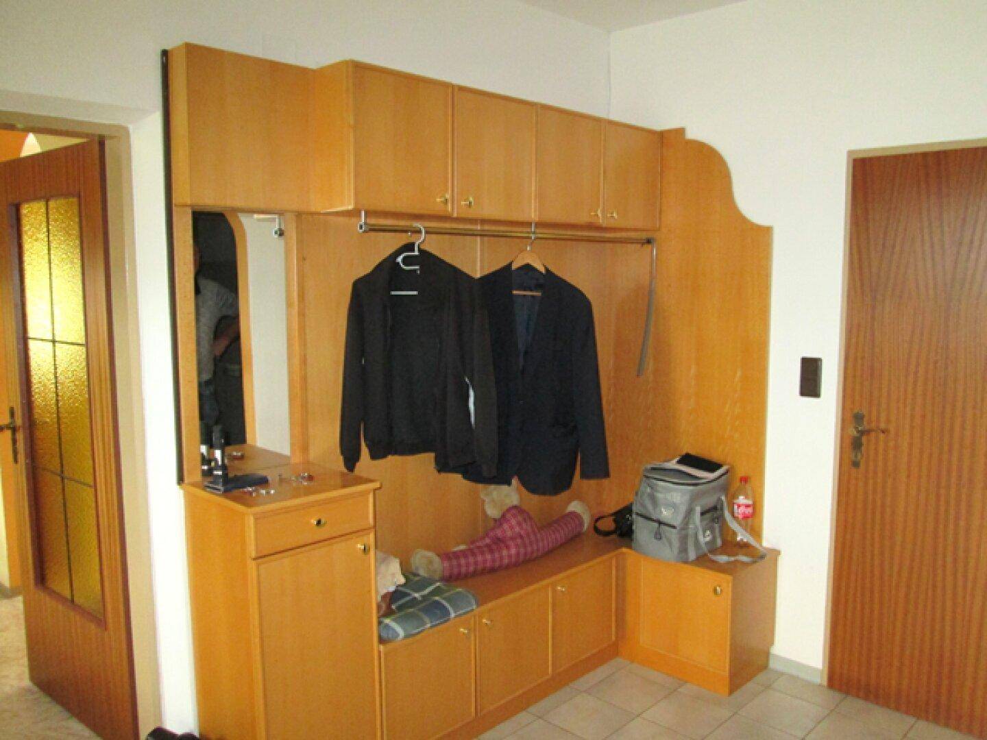 Eingangsbereich mit Garderobe, Holzschränken und Spiegel für praktische Nutzung und Stauraum.