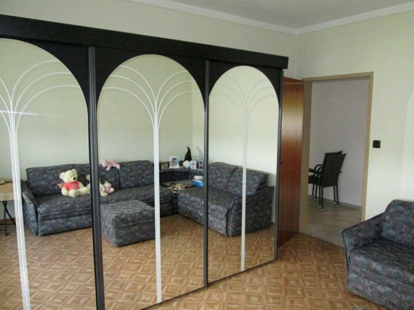Wohnzimmer mit Spiegelschränken, die den Raum optisch vergrößern, und Sofa.