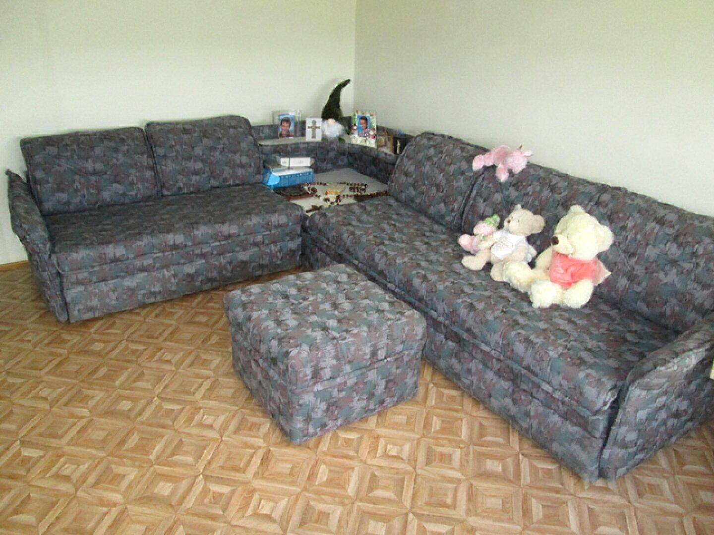 Gemütliches Wohnzimmer mit zwei Sofas und einem Hocker auf Laminatboden in neutralen Farben.